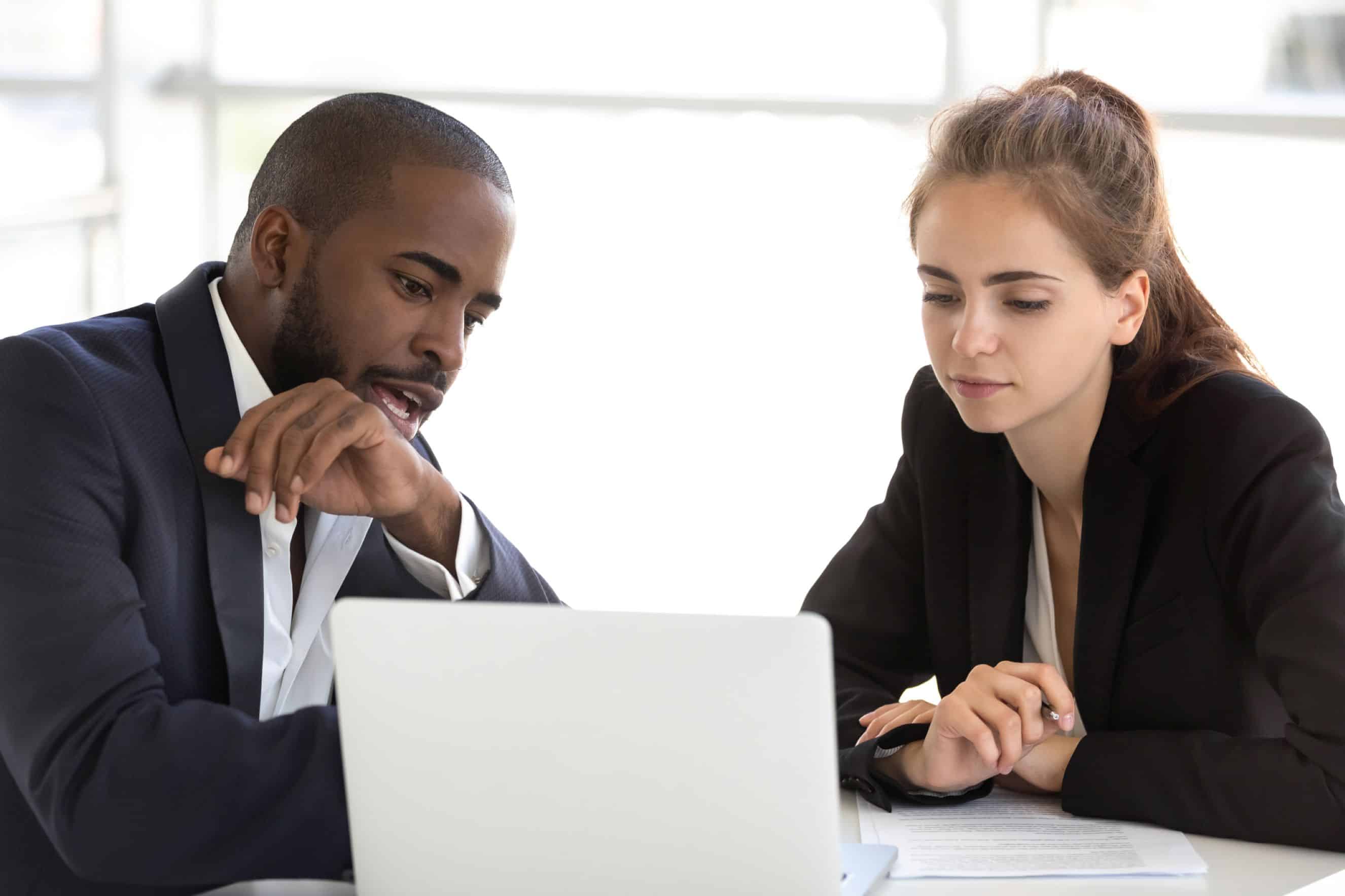 Professional coach guiding a client during a one-on-one coaching session at a laptop